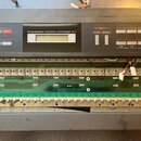 Černý syntetizátor s nápisem PROGRAMMABLE POLYPHONIC SYNTHESIZER JU-1. Na panelu jsou viditelné sekce EDIT, TONE MODIFY, GROUP PRESET MEMORY a BANK N…