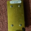 Zadní strana kytarového snímače v mosazném provedení. Na povrchu je vyražen nápis DIMARZIO PICKUPS MADE IN U.S.A a samostatné písmeno F. V horní část…