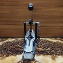 Fotografie zobrazuje jednopedálový basový pedál v černé a stříbrné barvě. Pedál má kovové provedení s vrstveným designem šlapky a viditelnou pružinou…