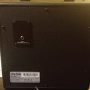 Zadní strana černého kytarového komba s texturovaným povrchem. V horní části je umístěn výstup s nápisem 4 OHM SPEAKER OUTPUT. Dole se nachází štítek…