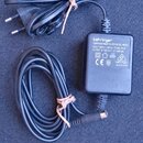 Černý napájecí adaptér s připojeným síťovým kabelem a konektorem. Na štítku je uveden nápis behringer, EURORACK POWER SUPPLY MODEL MXEU3, INPUT: 230V…