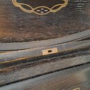 Detail tmavého dřevěného klavíru s viditnou strukturou slety. Na víku je zlatý dekorativní ornament a nad klávesnicí je v rámečku nápis KOCH & KORSEL…