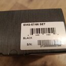 Fotografie zachycuje detail černé krabice s bílou papírovou nálepkou. Na nálepce je uveden text EMG-57/66 SET, BLACK a S/N: (21)0000000007064 spolu s…