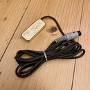 Kabel s kovovým, zlatavým obdélníkovým modulem, na kterém je vyryté logo a nápis Forte. Kabel je černý, viditelně znečištěný a svázaný bílou stahovac…