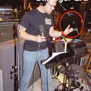 Fotografie zachycuje muže v nahrávacím studiu s mikrofonem v ruce. V pozadí je vidět černý kytarový zesilovač s bílým nápisem METALLICA, který je vyz…