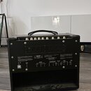 Zadní strana černého kytarového komba s koženým potahem a úchytem. Na zadním panelu jsou viditelné nápisy: "MAIN SWITCH", "SPEAKER OUTPUTS" (s označe…