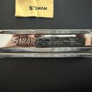 Chromatická harmonika s chromovaným kovovým povrchem. Na přední straně je vyryt nápis SWAN CHROMATIC 16-64 HARMONICA a logo s ptákem a nápisem Swan.…
