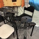 Elektronická bicí souprava s černým rámem a černými padovými plochami. Na pedálu je viditelný nápis ALESIS. Souprava obsahuje tři činely, dva tom-tom…
