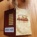 Papírový štít přivázaný k nástroji. Na přední straně je hnědý nápis Richwood a texty ALL HANDMADE FROM SELECTED TONEWOODS a Master Series. Zadní stra…