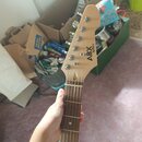 Fotografie zachycuje hmatník a hlavu elektrické kytary z přírodního světlého dřeva s tmavým hmatníkem. Na hlavě je umístěn nápis ABX guitars. Nástroj…