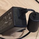 Černý síťový adaptér s připojeným cylindrickým konektorem. Na boku je uveden nápis CULINC, model DC-3h a označení EAC. Jsou zde dále viditelné různé…