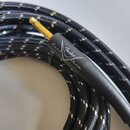 Černý kabel s pleteným povrchem a bílými detaily. Na černém konektoru se nachází zlatý hrot a bílý nápis Custom Shop s logem Fender. Povrch konektoru…