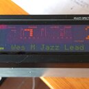 Detailní pohled na černý elektronický přístroj s nápisem MULTI SPECTRAL LCD DISPLAY. Displej zobrazuje červené a zelené texty a grafy, včetně nápisů…