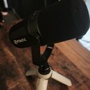 Černý kondenzátorový mikrofon s nasazenou černé molovou popfiltrovou krytkou. Na těle mikrofonu je bílý nápis FDUCE s logem vedle něj. Mikrofon je um…