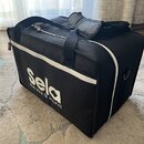 Černá transportní taška s bílým zipem a dvěma rukojtěmi. Na boku je bílý nápis Sela a pod ním menší text the soul of sound. Na boku je vidět malá čer…