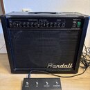 Černý kytarový kombo zesilovač s nápisem Randall na přední mřížce. Na horním ovládacím panelu je uveden model RG50TC a nápis 50 WATT TUBE COMBO. Před…