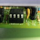 Detailní záběr na zelenou plošnicovou desku s elektronickými součástkami. Centrálně je umístěn černý integrovaný obvod s nápisem MN3007 a symbolem v…
