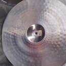 Kruhové činely z kovu s broušeným povrchem a jemným kladikováním. Na pravé straně je viditelné zlatavé logo Zildjian. V centru se nachází otvor s mal…