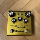 Zlatý kytarový efekt s nápisy Riverside multistage drive a strymon. Na horní straně jsou dva přepínače s označením GAIN (low, high) a PUSH (norm, mid…