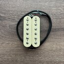 Fotografie znázorňuje humbucker snímač v krémové barvě s dvěma řadami šesti viditelných šroubů. Snímač má připojovací kabel v černém oplastu s odhale…