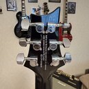 Zadní strana černé hlavy kytary s chromovanými ladičkami, na kterých je vyryto logo PRS. Na zadní straně hlavy je bílý nápis: Built by Cor-Tek Musica…