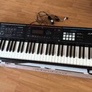 Černý digitální klavír s bílými a černými klávesami. Na pravé straně je bílý nápis Roland JUNO-DS a v sekci ovládání nápisy MODE, KEYBOARD a PHRASE P…