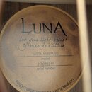 Kruhová štítková nálepka uvnitř akustického nástroje s nápisem LUNA. Pod logem je text „let your light shine!“ a podpis „Yvonne de Villiers“. Dále js…