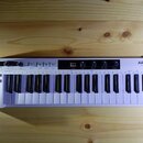Bílá klaviatura s logem ARTURIA a nápisem „the sound explorers“. Na levé straně se nachází čtyři černé otočné ovladače, několik tlačítek a v dolní čá…