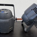 Dvě černé svítidla z plastu s nastavitelné nožní základnou. Levý kus má na horní straně ovládací panel s displejem, několika tlačítky a konektory. Na…