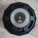 Zadní strana černého reproduktoru s kovovým magnetem. Na magnetu je černý kruhový štítek s bílým nápisem PRECISION DEVICES a menším textem Quite: Car…