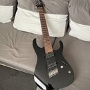 Černá elektrická kytara s lesklým povrchem a hnědým hmatníkem. Nástroj má dva humbuckery, jeden ovládací knoflík a přepínač. Na hlavě kytary jsou vid…