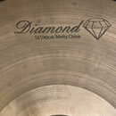 Detailní záběr na kovový činel s koncentrickými rýhami v povrchu. Na povrchu je černý nápis Diamond, pod kterým je text 16"/40cm Trinity China a graf…