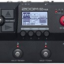 Černý basový procesor značky ZOOM, model B2 FOUR. Zařízení má digitální displej s nápisy Bass Driver PREAMP, DYNAMIC COMPRESSOR a GOAT2018, čtyři ovl…