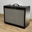 Černý kytarový kombozesilovač s texturovaným povrchem a šedou přední síťovkou. V horní části je umístěn nápis "Fender - Deluxe". Nástroj vykazuje min…