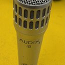Stříbrný dynamický mikrofon s kovovou mřížkou a perforovaným krytem hlavy. Na těle je černý nápis AUDIX i5 a níže vyryté číslo 25. Povrch vykazuje dr…