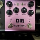 Fialový efekt pedál s nápisy DIG, dual digital delay a strymon. Na horní straně jsou čtyři černé otočné knoflíky s popisky TIME / TIME 2, TONE, REPEA…