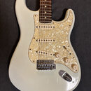 Elektrická kytara s bílým trupem a hnědým hmatníkem. Má tři snímače s bílými krytkami a perleťový pickguard. Na ovládacích knoflících jsou nápisy Vol…