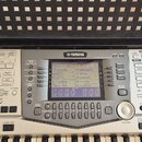 Digitální klavír značky YAMAHA s bílým šasi a černými klávesami. V horní části je umístěn displej s nápisem MAIN a různými ovládacími tlačítky rozděl…