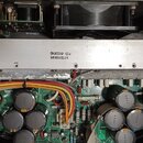 Fotografie zachycuje vnitřní elektroniku přístroje s viditelnými deskami plošných spojů, kondenzátory a barevným kabelážním zapojením. V horní části…