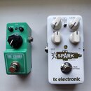 Dvě efektové pedály umístěné vedle sebe na bílém povrchu. Levý pedál je zelený s nápisy TUBE SCREAMER MINI, OVERDRIVE, TONE, LEVEL a značkou Ibanez.…