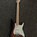 Elektrická kytara s tónem těla v provedení sunburst a světlým hřednicovým dřevě. Na hlavě je viditelné logo Fender. Kytara má bílý pickguard, tři sní…