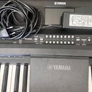 Černý digitální klavír značky YAMAHA s bílými a černými klávesami. Na ovládacím panelu jsou viditelné nápisy SONG CONTROL, AUTO, FADE, MASTER EQ, CHA…