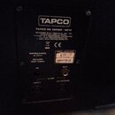 Fotografie zachycuje zadní panel černého elektronického zařízení. Je na něm vidět logo TAPCO a nápis TAPCO 60 SERIES / 6915, dále údaje IMPEDANCE 8 O…