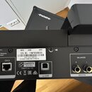Detail zadní strany černého elektronického zařízení s různými konektory. Na stříbrném štítku jsou nápisy MFD. JUNE 2020, SER. NO. TFMP00606EH a model…