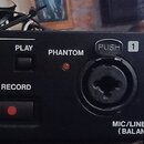 Černý rackový zvukový záznamový přístroj s ovládacími prvky. Na předním panelu jsou tlačítka Menu, Browse, Stop/Home, Play a Record, červený otočný o…