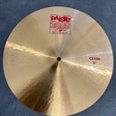 Zlatavý kovový činel s viditelným rýhováním povrchu. Na horní části je červené logo PAiste 2002 s nápisy TRADE MARK a MADE IN SWITZERLAND. V pravé čá…