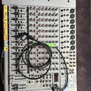 Stříbrný mixážní pult s mnoha ovládacími knoflíky, posuvníky a konektory. Na levé straně jsou žluté štítky s nápisy F, TEL., K, HDMI, SAX, AVMIXER a…