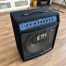 Černý basový kombo zesilovač s modrým ovládacím panelem a kovovou mřížkou. Na horní části je nápis EBS DROME PROFESSIONAL BASS COMBO 750 W a DEVELOPE…
