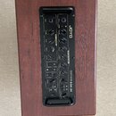 Akustický kytarový kombozesilovač v dřevěném korpusu hnědé barvy. Na černém ovládacím panelu je nápis JOYO a označení ACOUSTIC GUITAR AMP LIFIER BSK-…