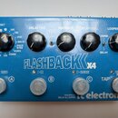 Modrý efekt pedál s nápisem FLASHBACK X4 a logem tc electronic. Na horní straně se nachází pět černých otočných ovladačů s popisky TONEPRINT, DELAY T…